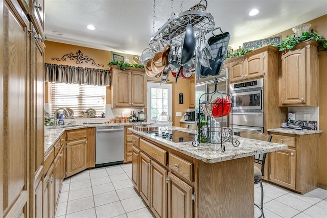 kitchen featuring sink, stainless steel appliances, light tile patterned floors, a breakfast bar, and a kitchen island