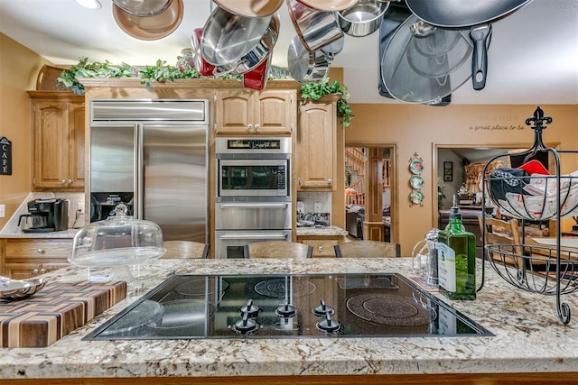 kitchen with light stone counters, light brown cabinetry, and appliances with stainless steel finishes