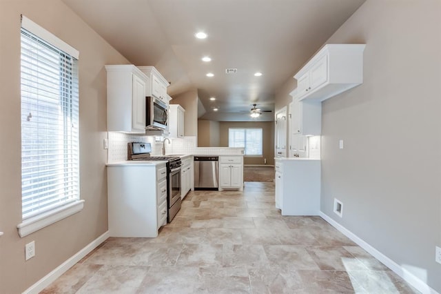 kitchen with tasteful backsplash, ceiling fan, white cabinets, and stainless steel appliances