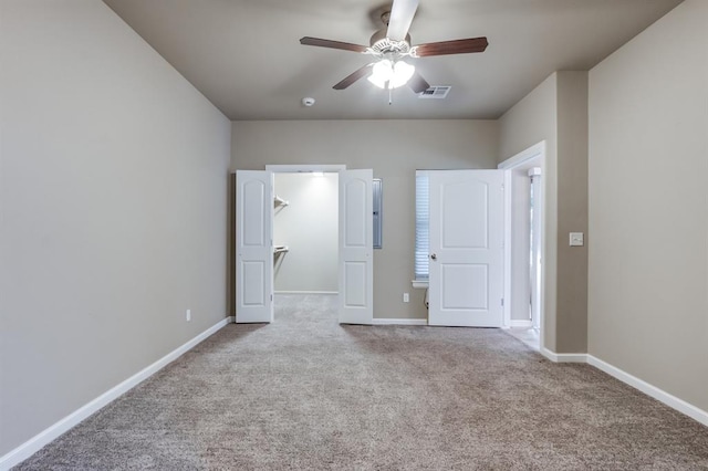 unfurnished bedroom featuring ceiling fan, light colored carpet, and a walk in closet