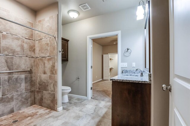 bathroom with tiled shower, vanity, and toilet