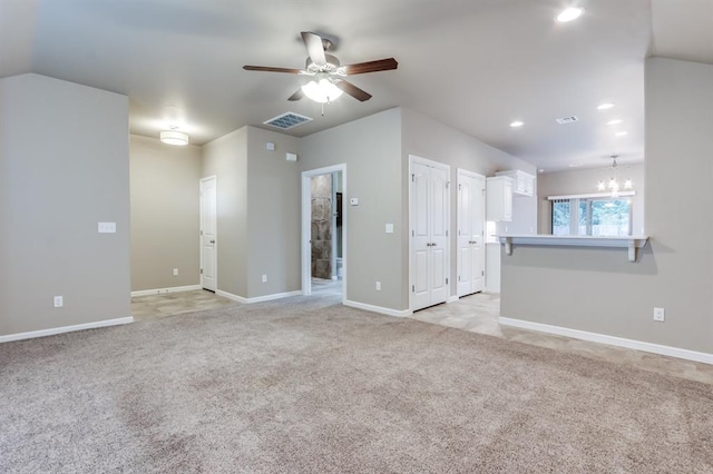 unfurnished living room featuring light carpet and ceiling fan with notable chandelier