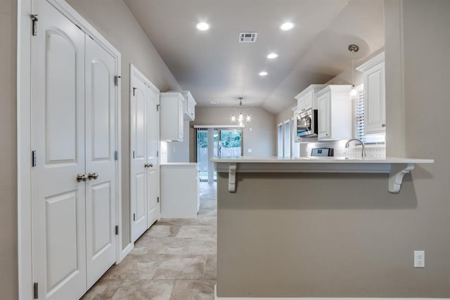 kitchen with a breakfast bar area, kitchen peninsula, and white cabinetry