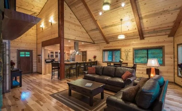 living room featuring beam ceiling, wood walls, wooden ceiling, and light wood-type flooring