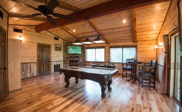 playroom with wood ceiling, lofted ceiling with beams, a fireplace, light hardwood / wood-style floors, and wood walls