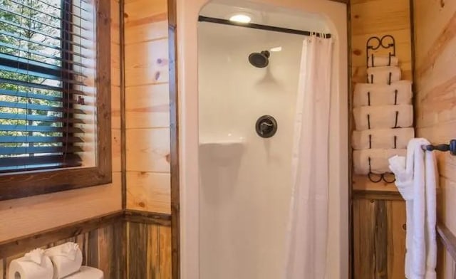 bathroom featuring wood walls and a shower with shower curtain