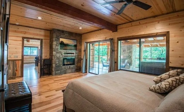 bedroom featuring multiple windows, hardwood / wood-style floors, beamed ceiling, and a fireplace