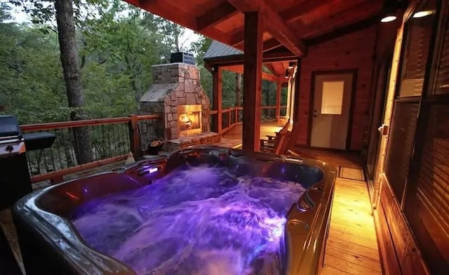 wooden terrace with an outdoor stone fireplace and a hot tub