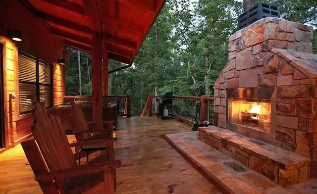 wooden deck featuring an outdoor stone fireplace and area for grilling