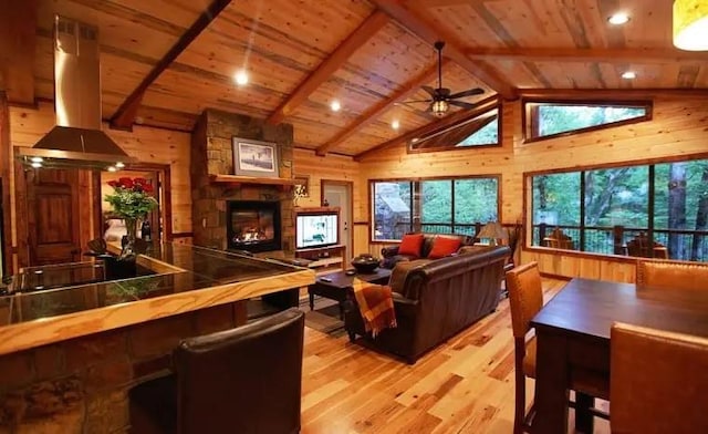 living room featuring lofted ceiling with beams, wood walls, and light hardwood / wood-style floors