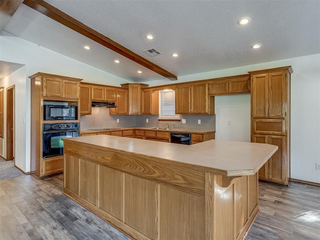 kitchen featuring vaulted ceiling with beams, a large island, light hardwood / wood-style flooring, and black appliances