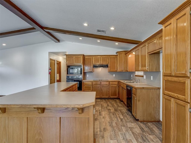 kitchen featuring sink, lofted ceiling with beams, a kitchen bar, black appliances, and light wood-type flooring