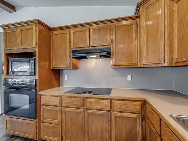 kitchen with black appliances, vaulted ceiling with beams, sink, and hardwood / wood-style flooring