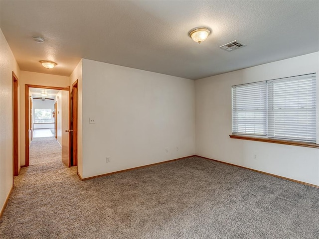 unfurnished room featuring a textured ceiling and light colored carpet