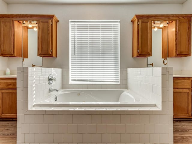 bathroom with hardwood / wood-style floors, vanity, and tiled bath