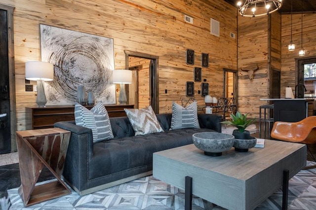 living room with wooden walls, high vaulted ceiling, a notable chandelier, and parquet flooring