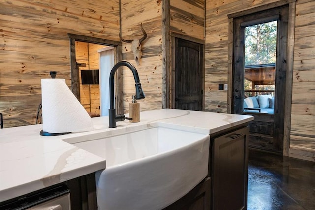 interior space featuring concrete floors, wood walls, and sink