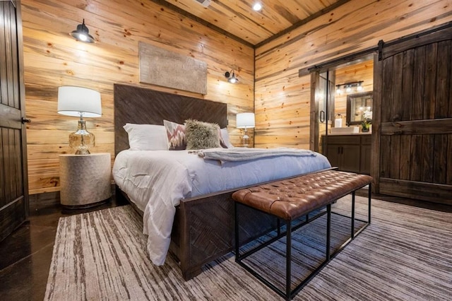 bedroom featuring a barn door, wooden walls, ensuite bath, and wooden ceiling