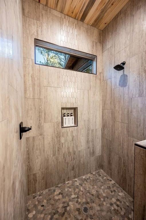 bathroom featuring a tile shower and wood ceiling