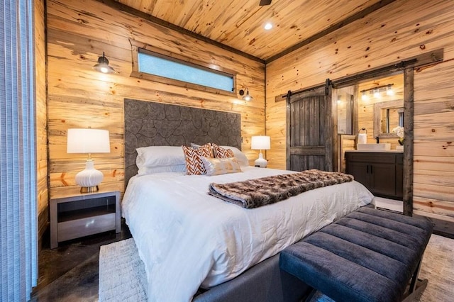 bedroom featuring ensuite bathroom, wood ceiling, a barn door, dark hardwood / wood-style floors, and wood walls