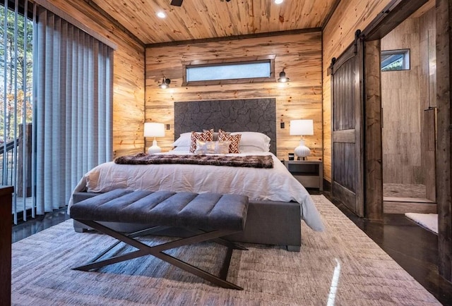 bedroom with wooden walls, a barn door, dark hardwood / wood-style floors, and wooden ceiling