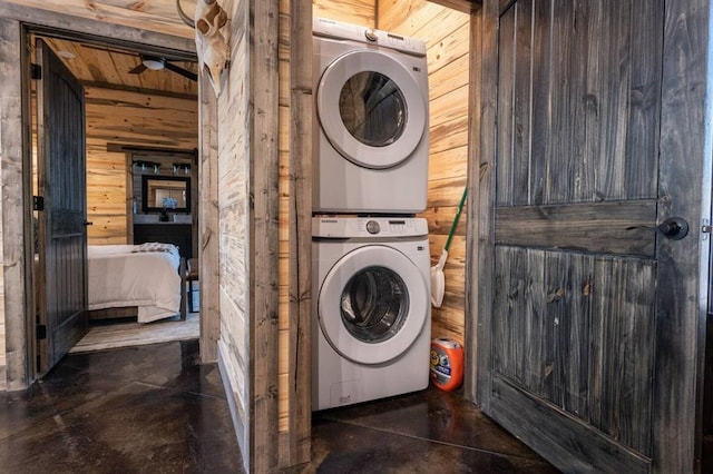 washroom with wood walls and stacked washer and dryer