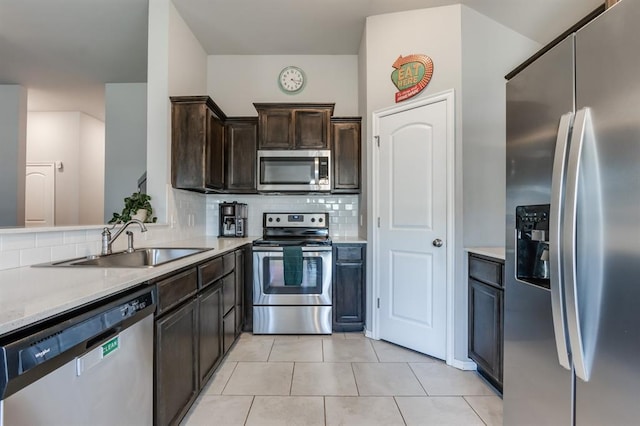 kitchen with tasteful backsplash, light tile patterned floors, sink, dark brown cabinets, and stainless steel appliances