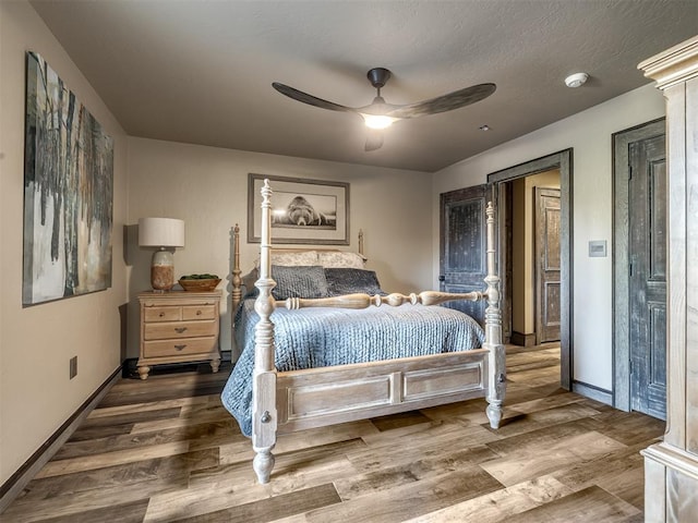 bedroom with ceiling fan, wood-type flooring, and a textured ceiling