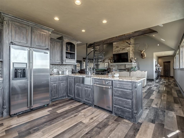 kitchen with high end refrigerator, lofted ceiling with beams, dark hardwood / wood-style floors, light stone countertops, and kitchen peninsula