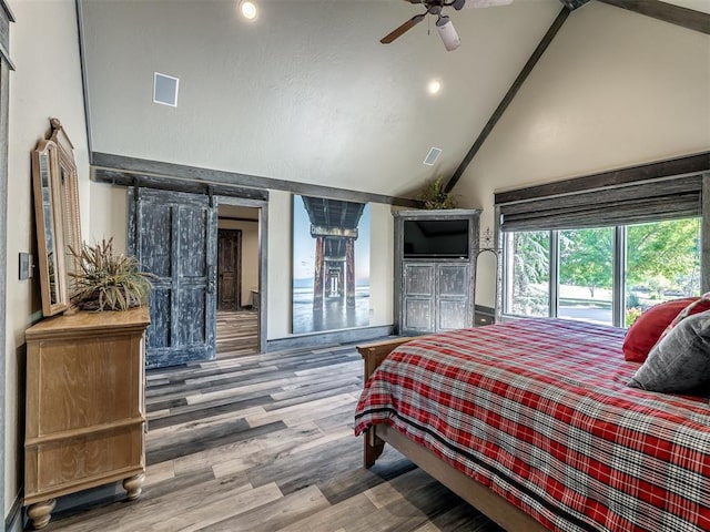 bedroom featuring wood-type flooring, a barn door, high vaulted ceiling, and ceiling fan