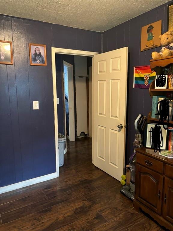 corridor with a textured ceiling, wood walls, and dark hardwood / wood-style floors