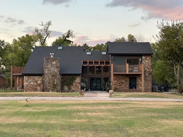 view of front of home featuring a yard, french doors, a balcony, and central AC unit