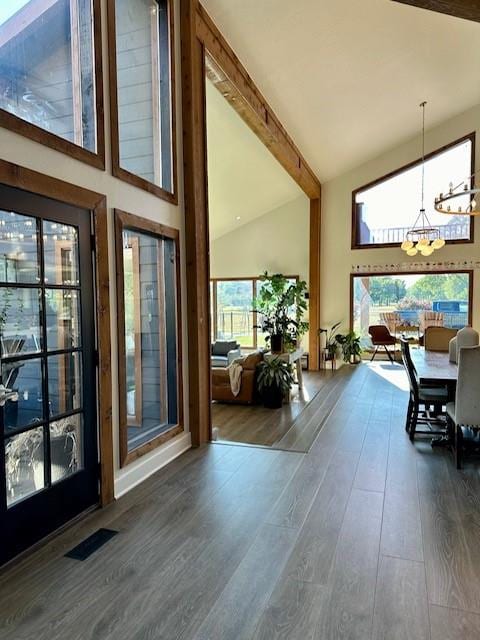 dining room featuring dark hardwood / wood-style floors, a healthy amount of sunlight, beam ceiling, and a chandelier