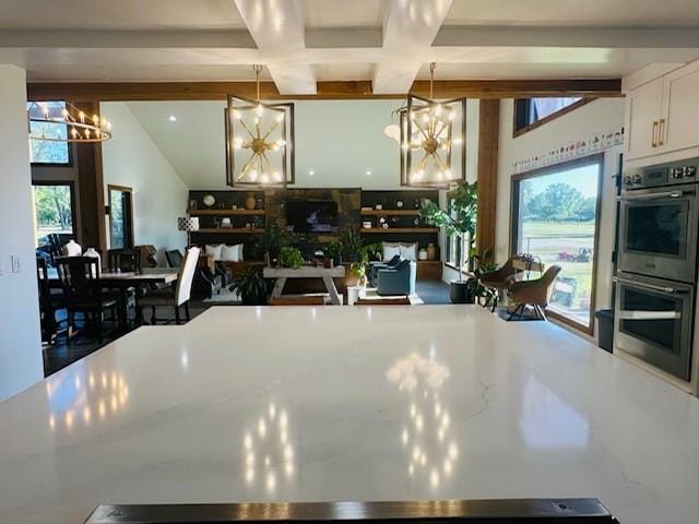 kitchen with coffered ceiling, stainless steel double oven, beam ceiling, decorative light fixtures, and white cabinetry