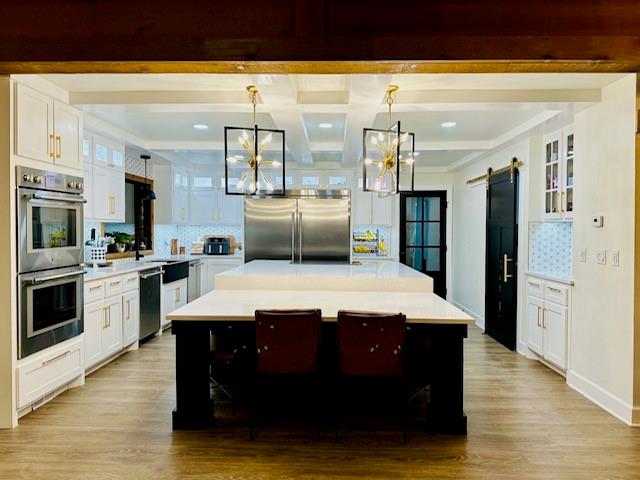 kitchen featuring a barn door, stainless steel appliances, a kitchen island, and tasteful backsplash