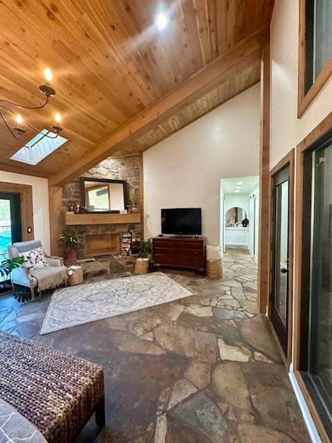 living room featuring a stone fireplace, lofted ceiling with skylight, and wood ceiling