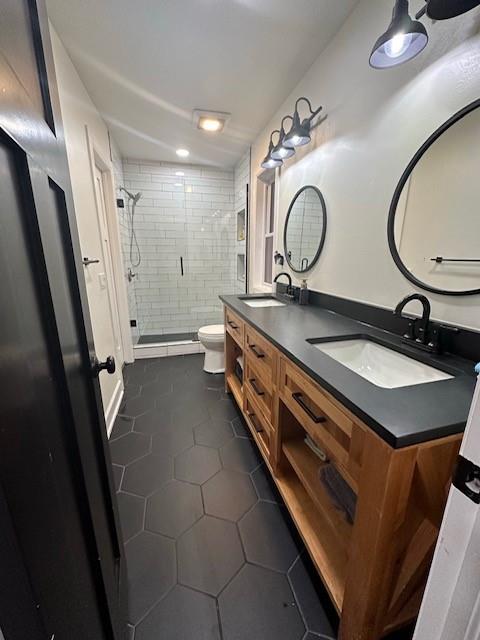 bathroom featuring toilet, a tile shower, vanity, and tile patterned floors