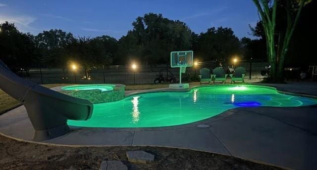 pool at dusk with a patio, an in ground hot tub, and a water slide