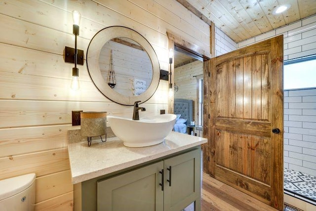 bathroom with vanity, wood walls, toilet, and wood-type flooring