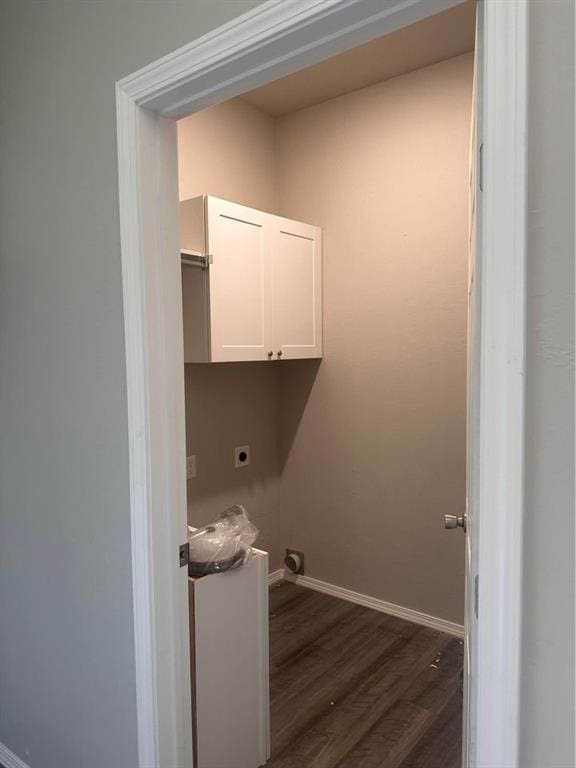 clothes washing area featuring electric dryer hookup, dark wood-type flooring, and cabinets