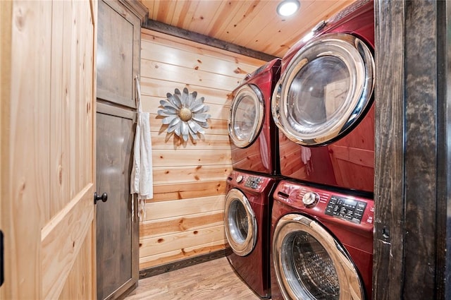 laundry room with wooden ceiling, wood finished floors, stacked washer and clothes dryer, and wooden walls