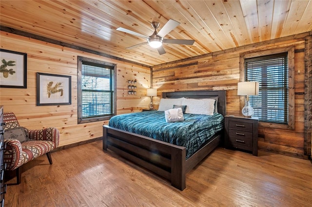 bedroom with wooden ceiling, a ceiling fan, wood finished floors, and wood walls