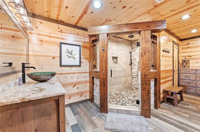 bathroom with wooden walls, wood finished floors, vanity, wood ceiling, and a shower stall