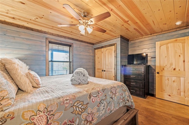 bedroom featuring light wood-style floors, wooden ceiling, ceiling fan, and wooden walls