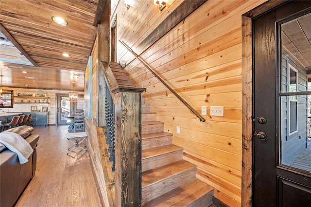 stairs featuring recessed lighting, wood ceiling, wooden walls, and wood finished floors