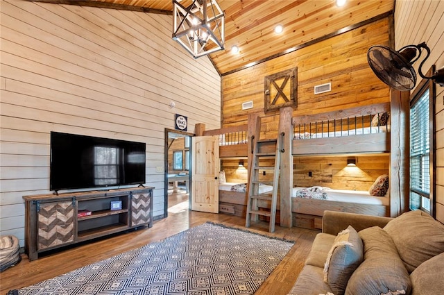 bedroom featuring high vaulted ceiling, wood walls, and wood finished floors