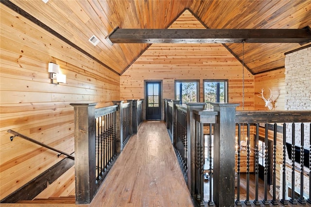 hallway with wood ceiling, wood finished floors, vaulted ceiling with beams, an upstairs landing, and wood walls