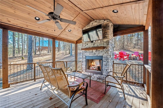 sunroom / solarium with a healthy amount of sunlight, wooden ceiling, an outdoor stone fireplace, and lofted ceiling