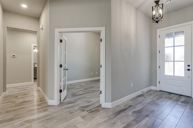 foyer with light hardwood / wood-style floors and an inviting chandelier