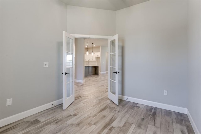 unfurnished room with french doors and light hardwood / wood-style flooring